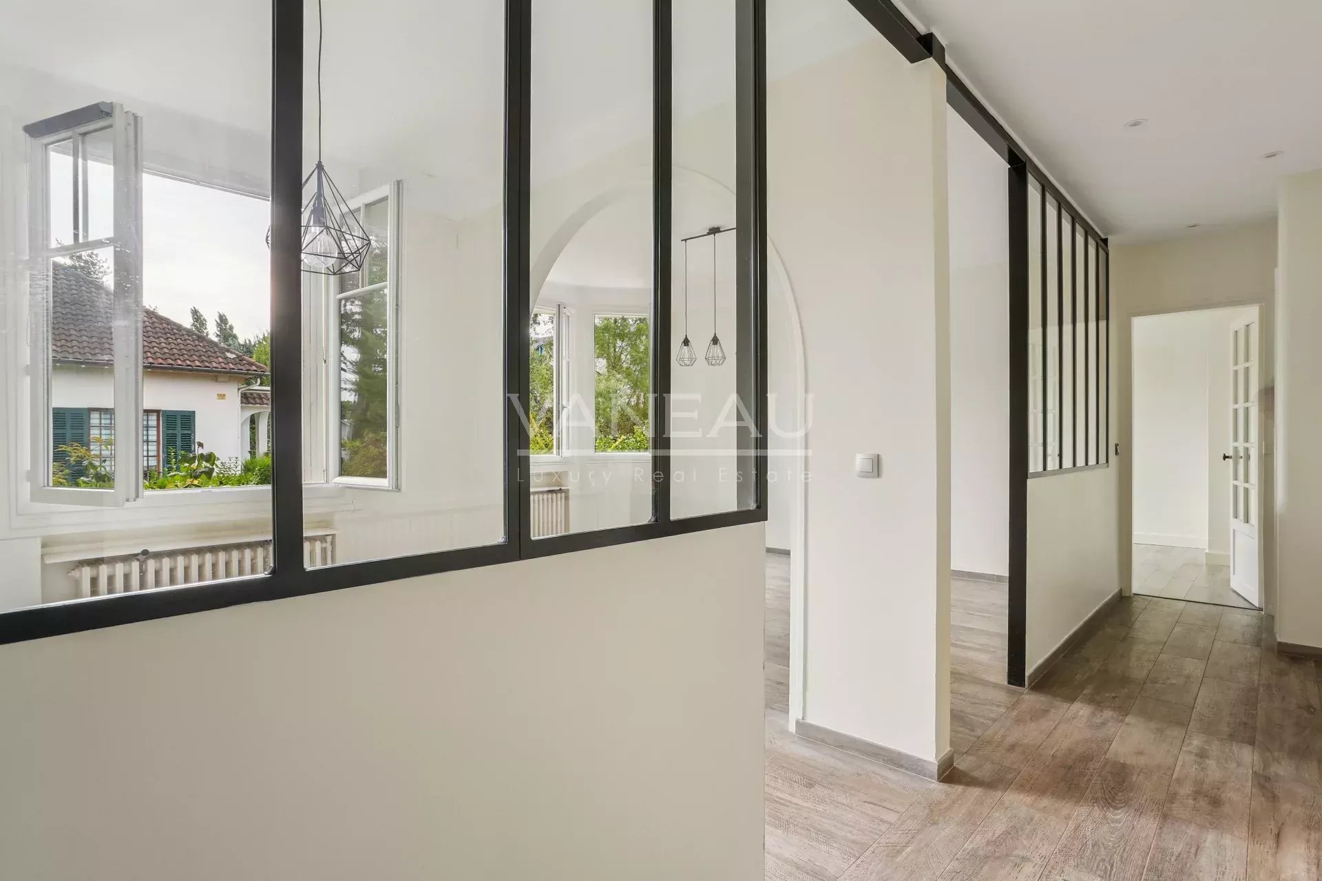 Intérieur d’une maison familiale à Sceaux Intérieur d'une maison rénovée avec des murs en verre et un sol en bois.