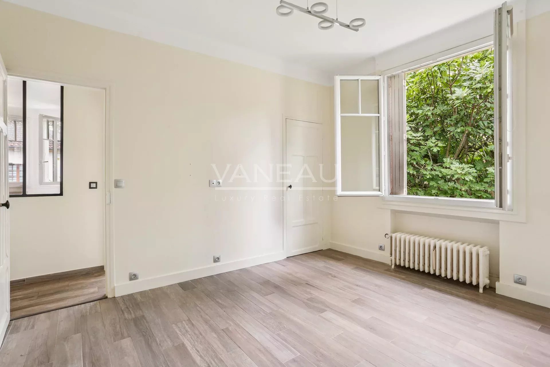 Intérieur d’une maison familiale à Sceaux Intérieur d'une maison rénovée avec une fenêtre donnant sur un jardin verdoyant.