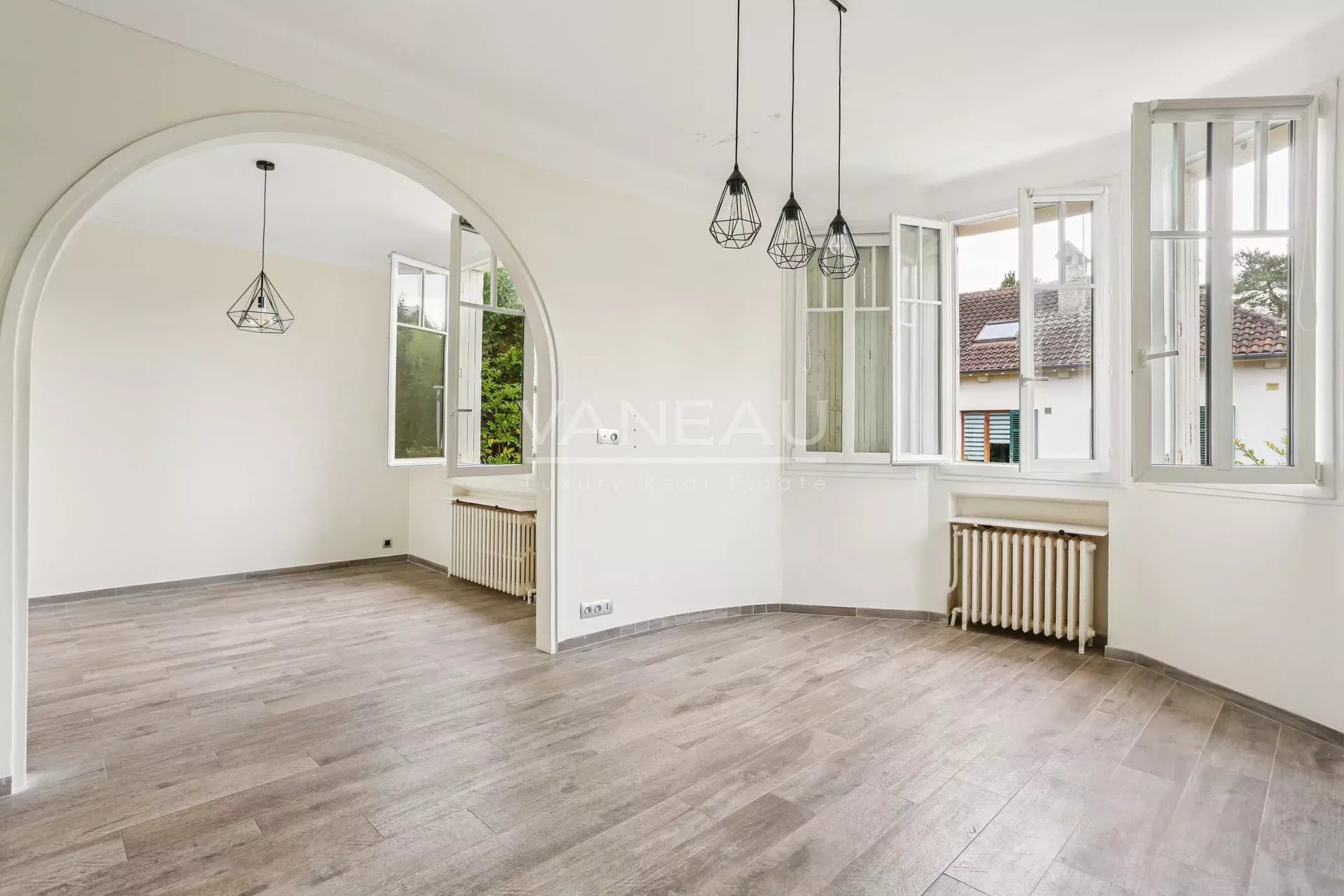 Intérieur d’une maison familiale à Sceaux Intérieur d'une maison rénovée avec un séjour lumineux et des fenêtres ouvertes.