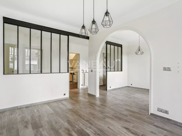 Intérieur d'une maison rénovée avec un sol en carrelage et des luminaires modernes.