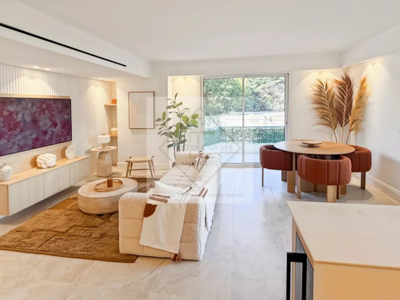 Open living room with a wall-mounted TV, beige sectional, and a round coffee table on a brown rug in a bright, modern space.