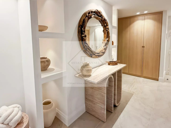 Modern foyer with a circular wooden-framed mirror above a marble console and built-in shelves displaying pottery.
