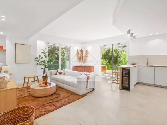 Bright open-plan living room with a white sofa, round coffee table, and large windows looking out to greenery.