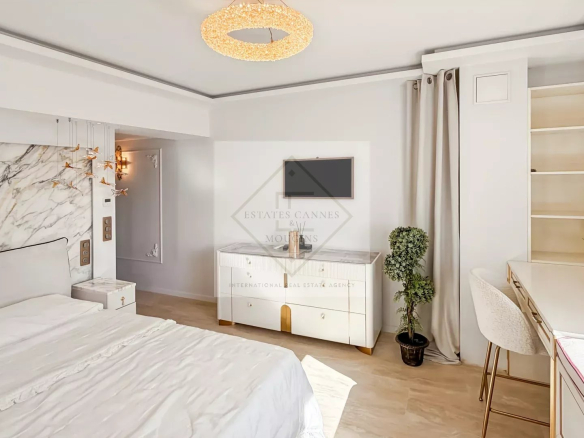 Luxurious white bedroom with marble headboard, gold accents and circular chandelier over a king bed with white bedding.