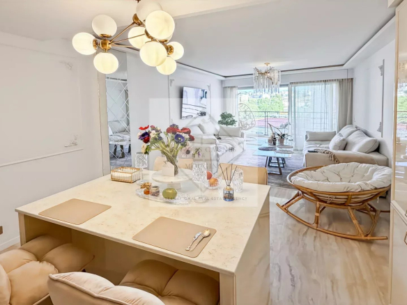 Bright open-plan kitchen and living area with a marble island, cream chairs, and a modern chandelier.