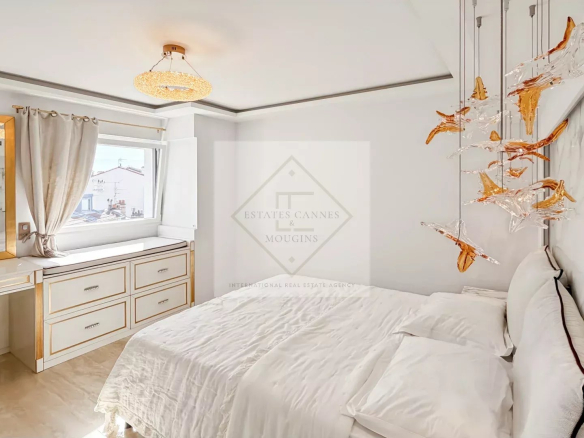 Luxurious white bedroom with gold-accent furniture, marble wall, and a white bed with plush pillows under an orange glass chandelier.