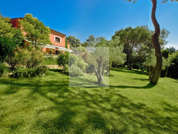 Villa spacieuse avec jardin verdoyant à Mougins, entourée d'arbres et de verdure.