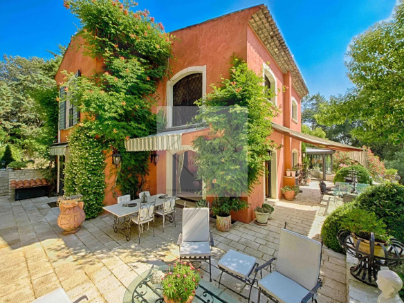 Villa colorée avec jardin à Mougins, entourée de verdure et de terrasses.