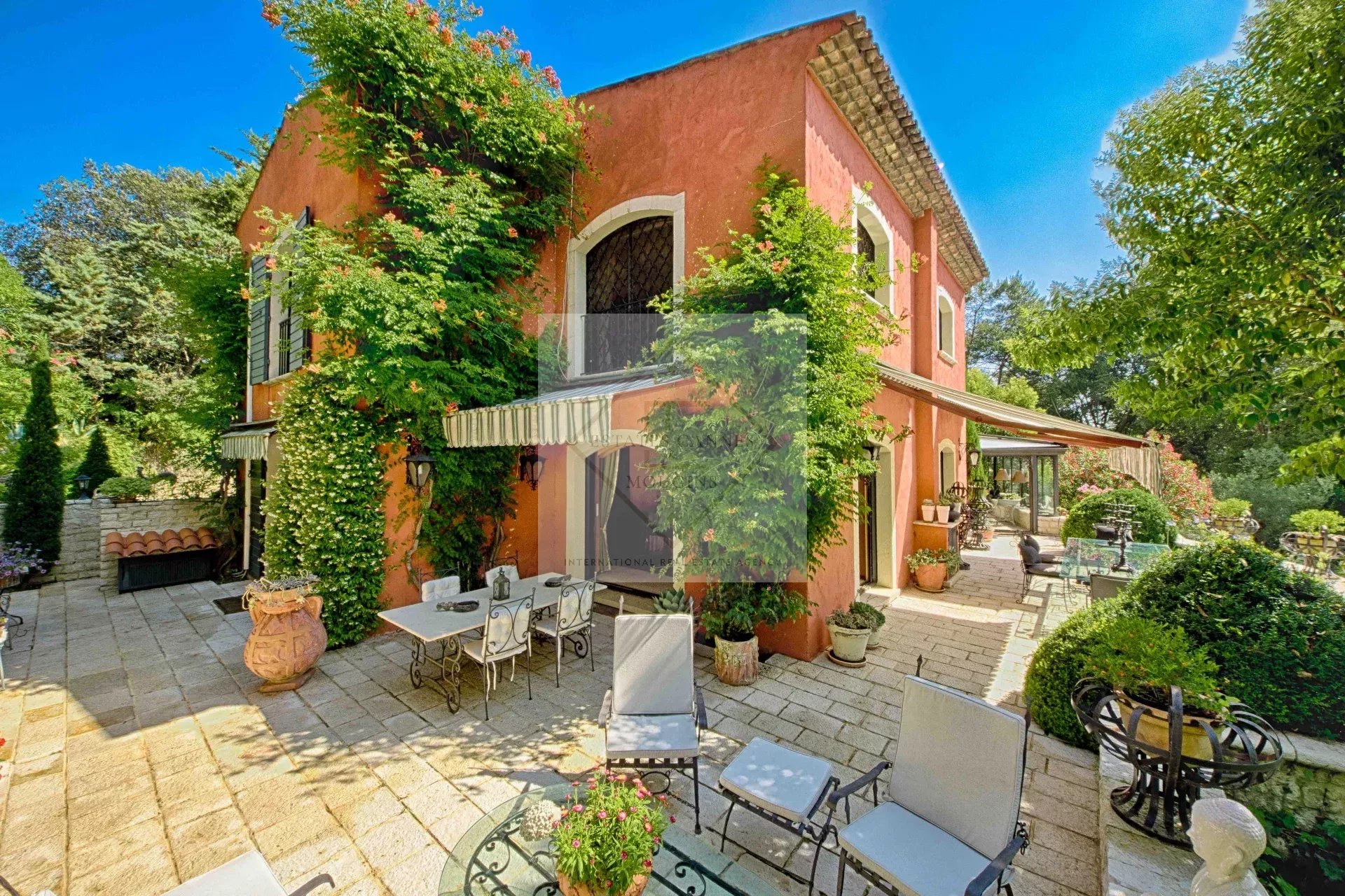 Villa colorée avec jardin à Mougins, entourée de verdure et de terrasses.