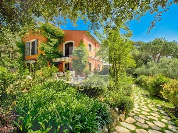 Villa spacieuse avec jardin verdoyant à Mougins, entourée de plantes et d'arbres.