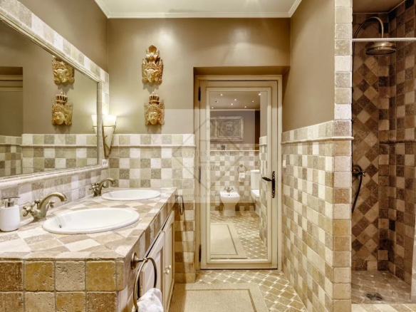 Salle de bain d'une villa à Mougins, avec carrelage en pierre et double vasque.