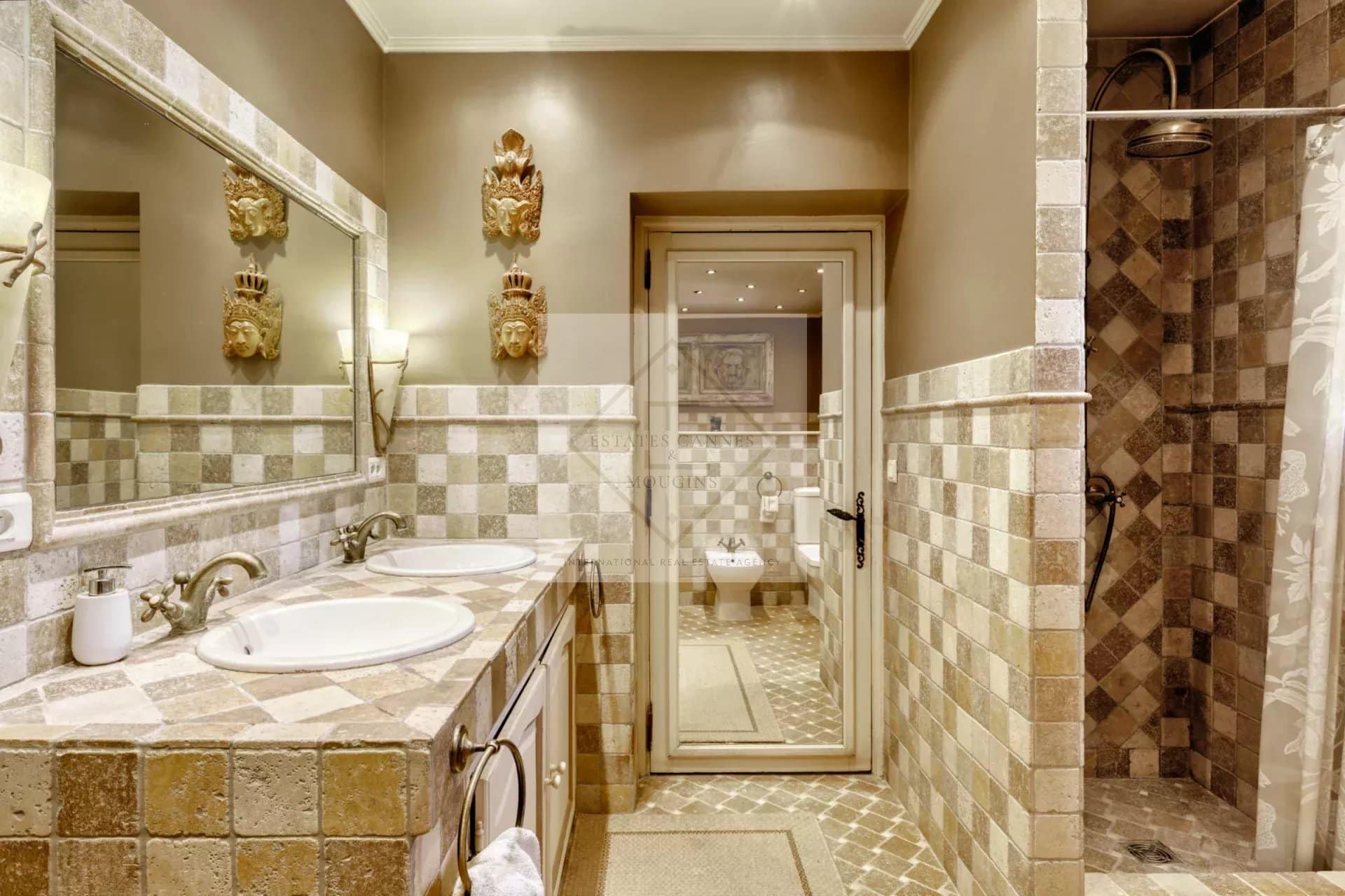 Salle de bain d'une villa à Mougins, avec carrelage en pierre et double vasque.