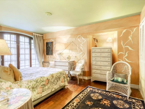 Chambre d'une villa à Mougins, avec lit, meubles en bois et décoration florale.