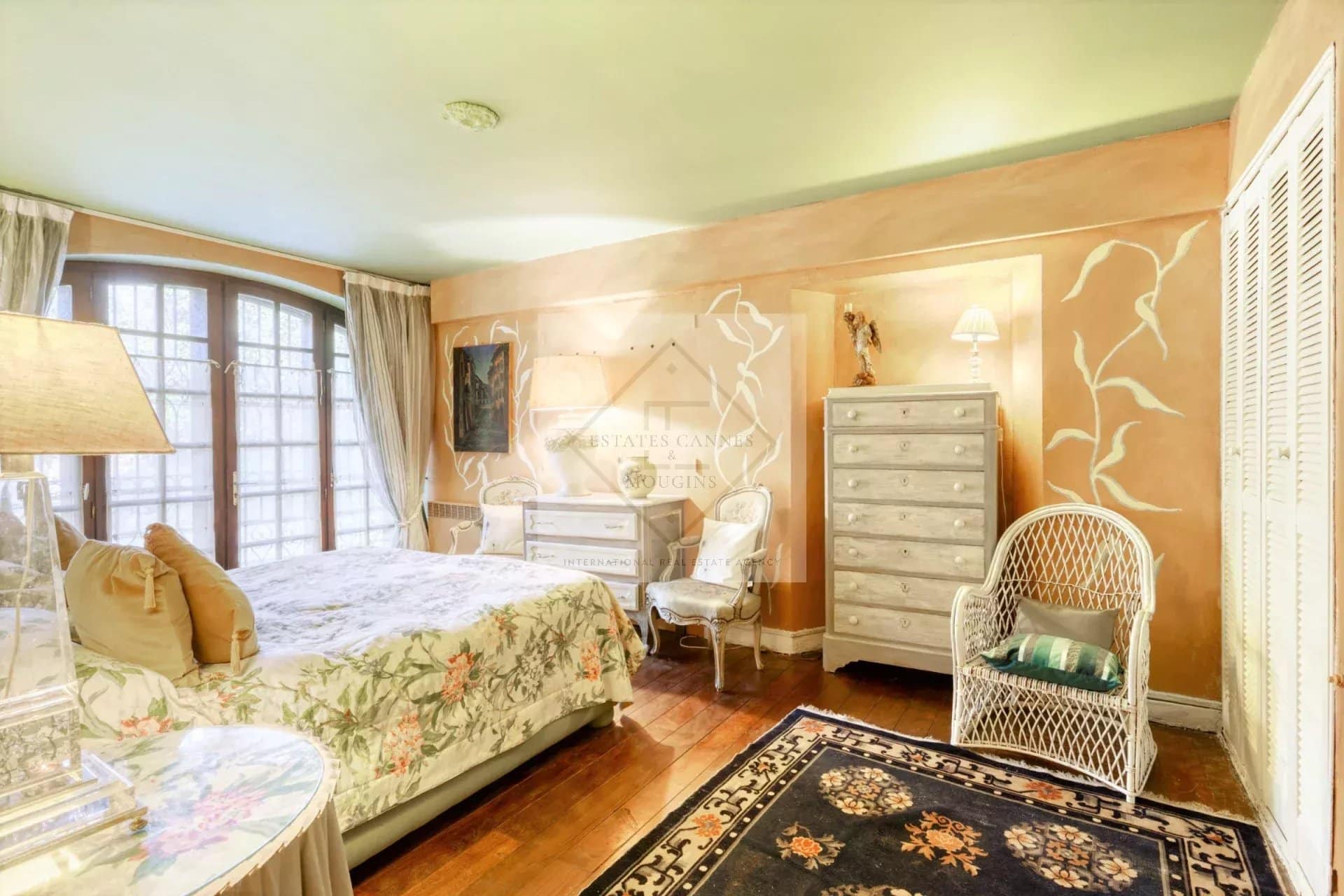 Chambre d'une villa à Mougins, avec lit, meubles en bois et décoration florale.