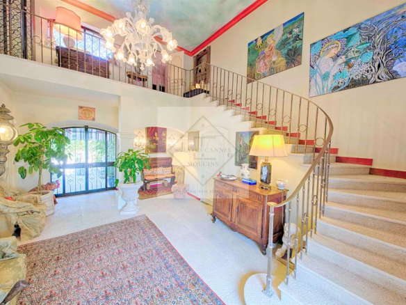Intérieur d'une villa à Mougins avec un escalier en colimaçon et des œuvres d'art au mur.