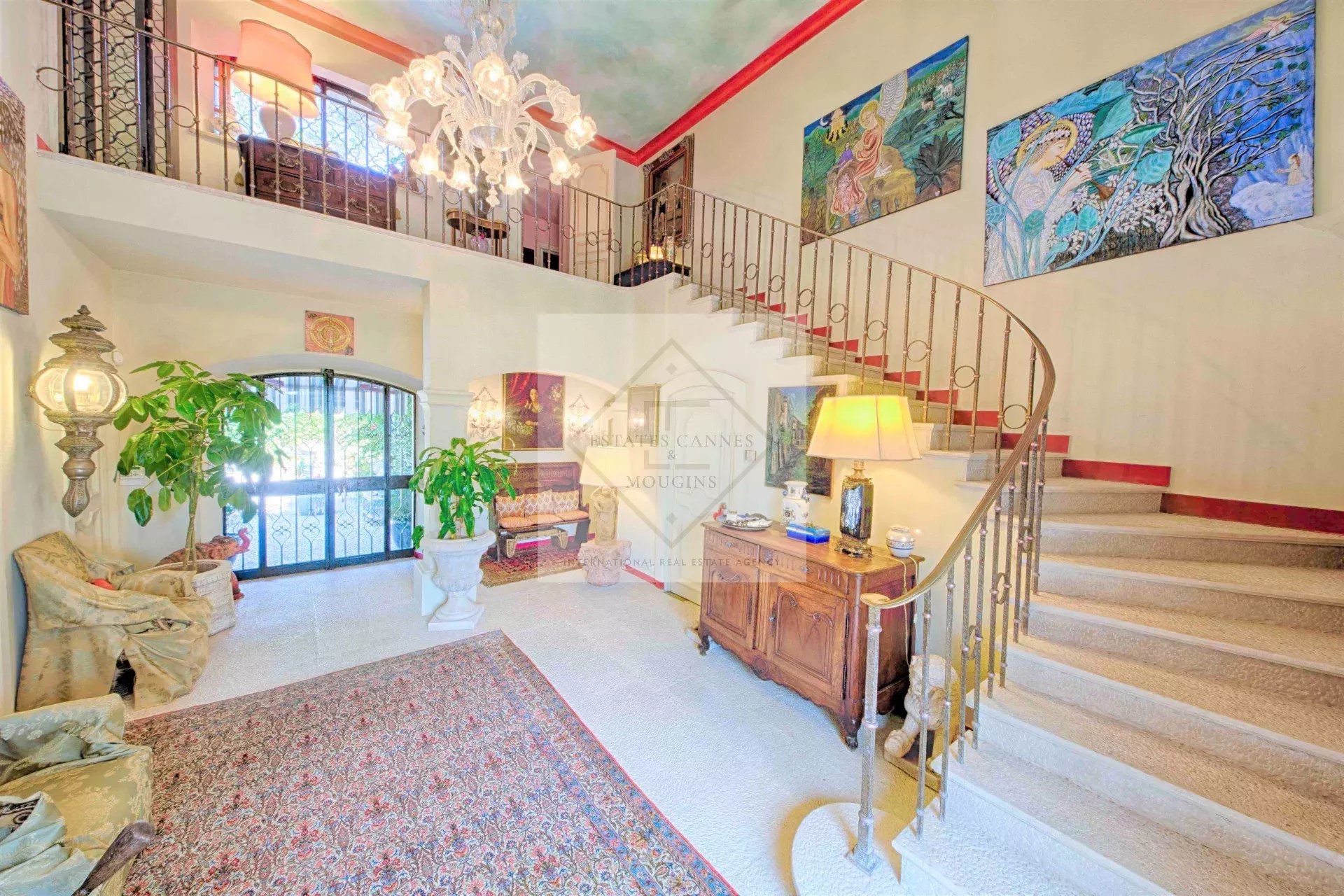 Intérieur d'une villa à Mougins avec un escalier en colimaçon et des œuvres d'art au mur.