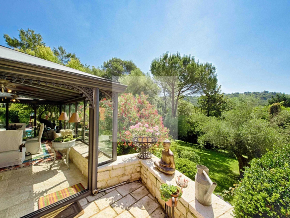 Vue d'une villa avec jardin à Mougins, entourée d'arbres et de fleurs.