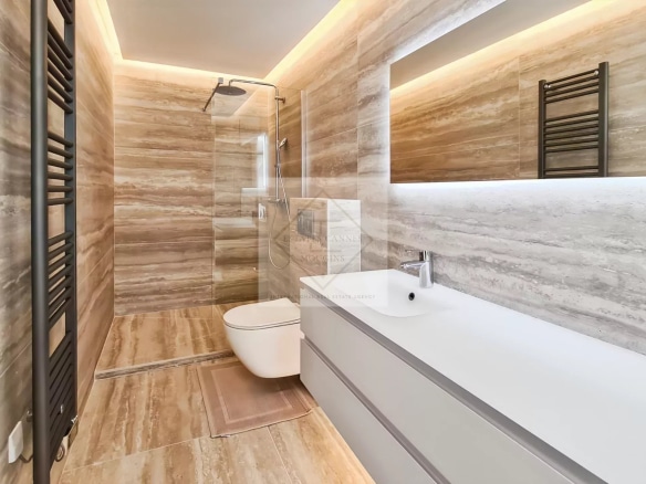 Salle de bain moderne avec douche et lavabo, décorée en marbre beige.