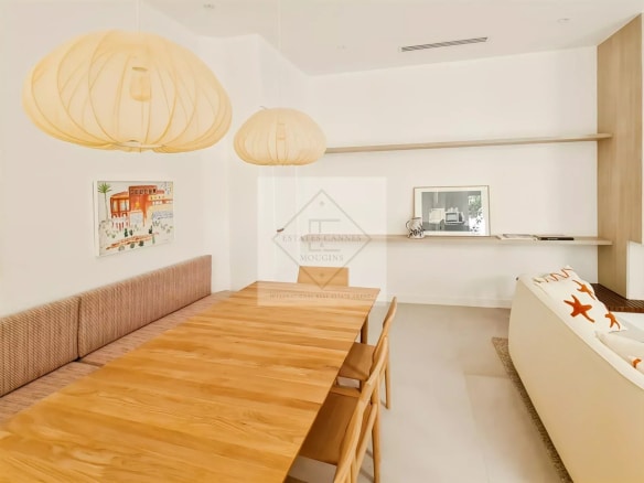 Intérieur d'une maison de ville à Cannes avec une grande table en bois et des lampes suspendues.