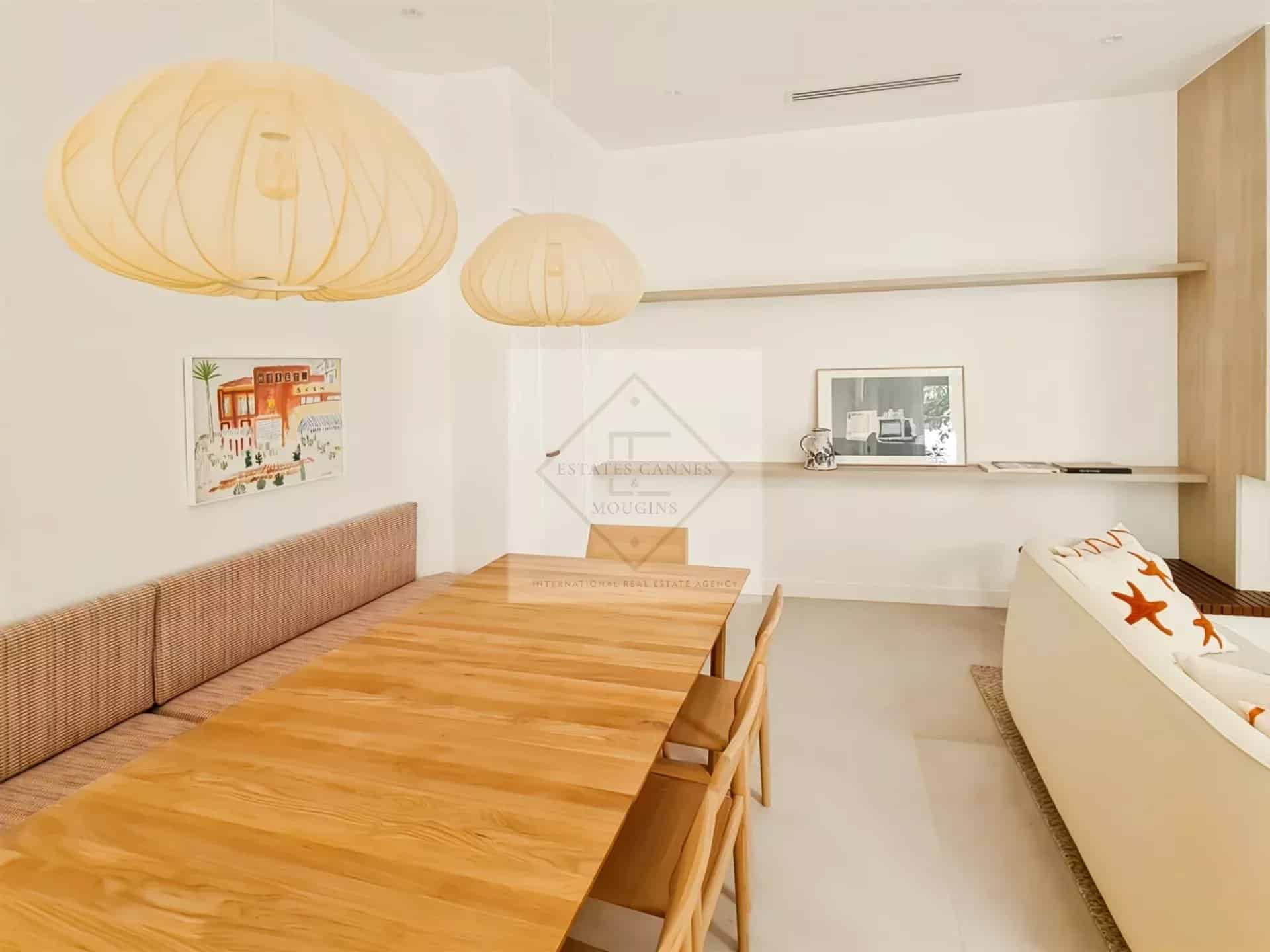 Intérieur d'une maison de ville à Cannes avec une grande table en bois et des lampes suspendues.