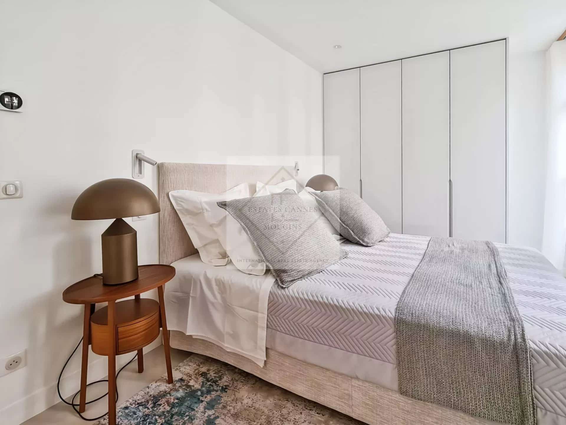 Chambre d'une maison de ville rénovée à Cannes, avec lit, lampe et placard.