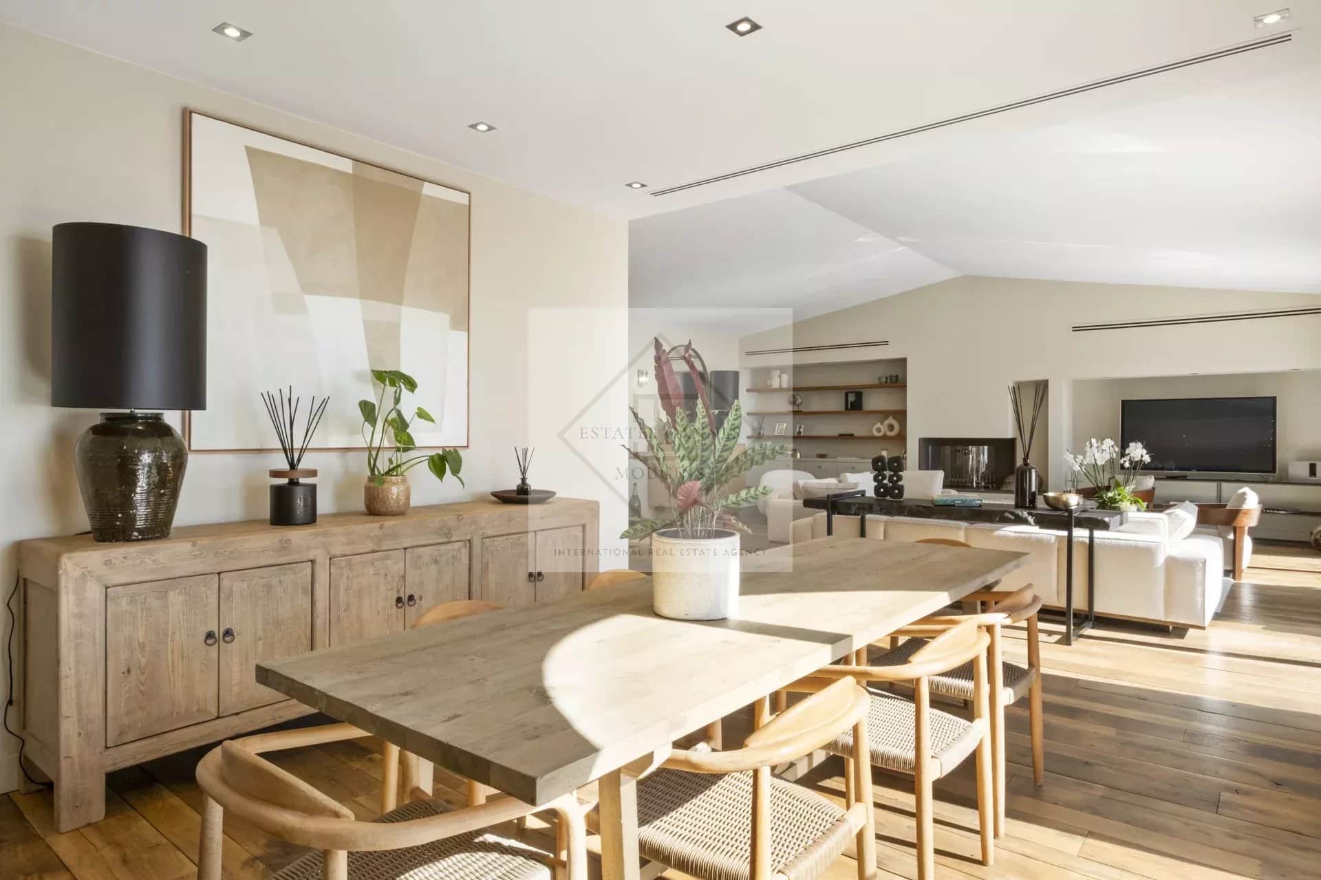Interior of a spacious villa with a wooden dining room and a modern living room.