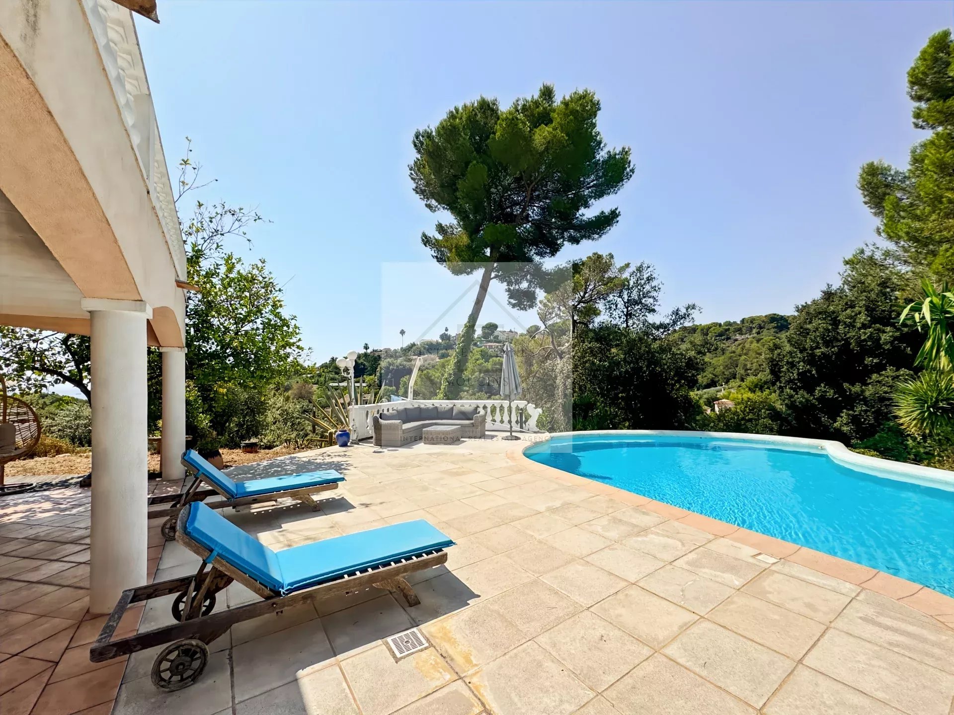 View from the pool and terrace of a villa in Antibes, surrounded by greenery.