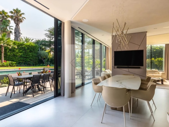 Intérieur d'une villa contemporaine avec salle à manger et vue sur le jardin paysager.