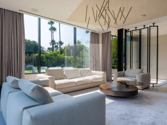 Intérieur d'une villa contemporaine avec un salon lumineux et des grandes fenêtres donnant sur le jardin.
