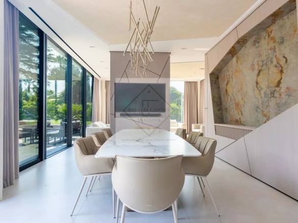 Intérieur d'une villa contemporaine avec salle à manger moderne et baies vitrées donnant sur l'extérieur.