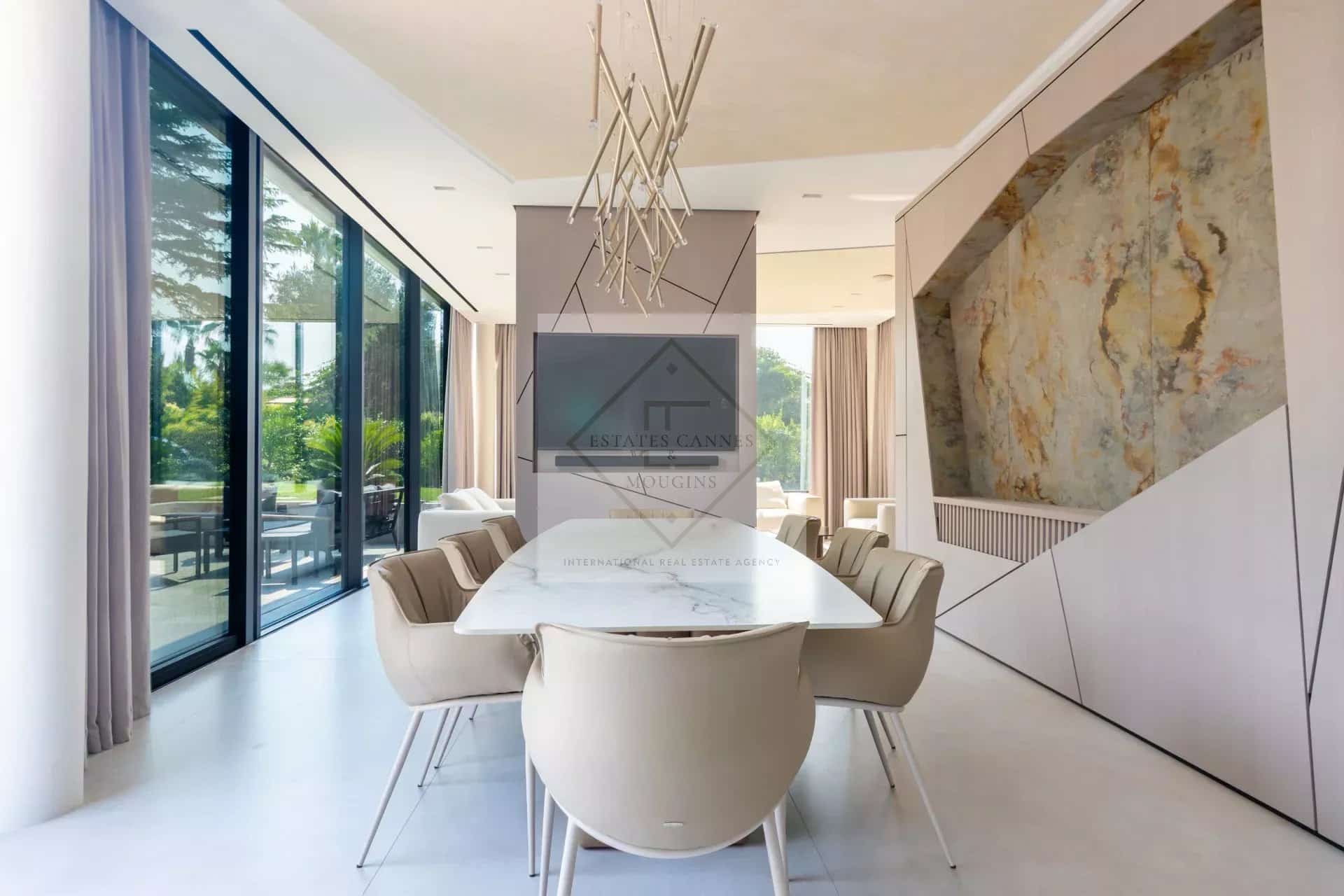 Intérieur d'une villa contemporaine avec salle à manger moderne et baies vitrées donnant sur l'extérieur.