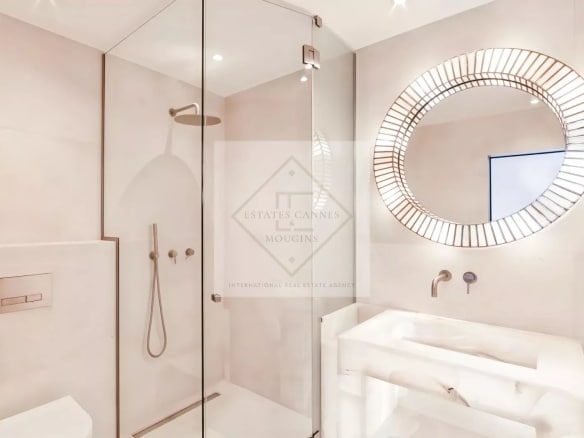 Salle de bain moderne avec douche à l'italienne et miroir rond.
