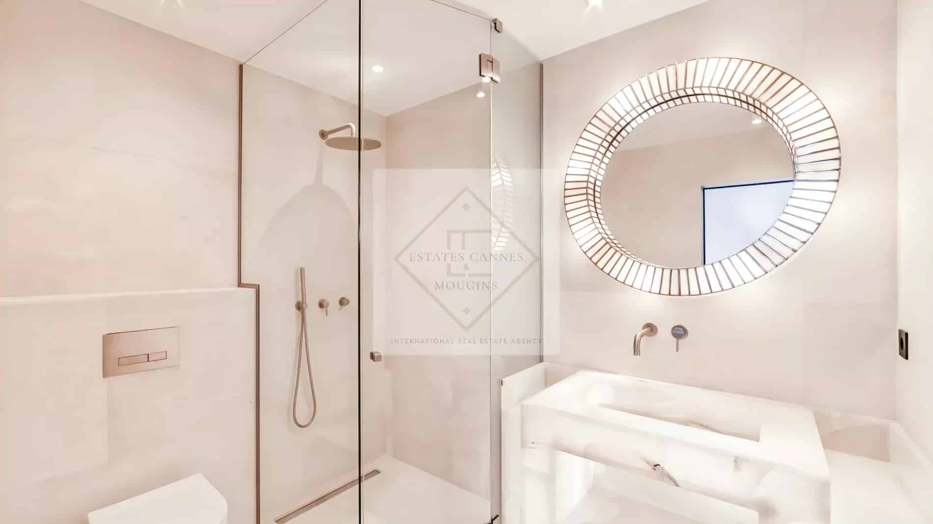 Salle de bain moderne avec douche à l'italienne et miroir rond.