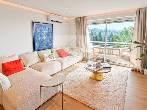 Salon lumineux d'un appartement rénové avec vue sur la mer, canapé et table basse.