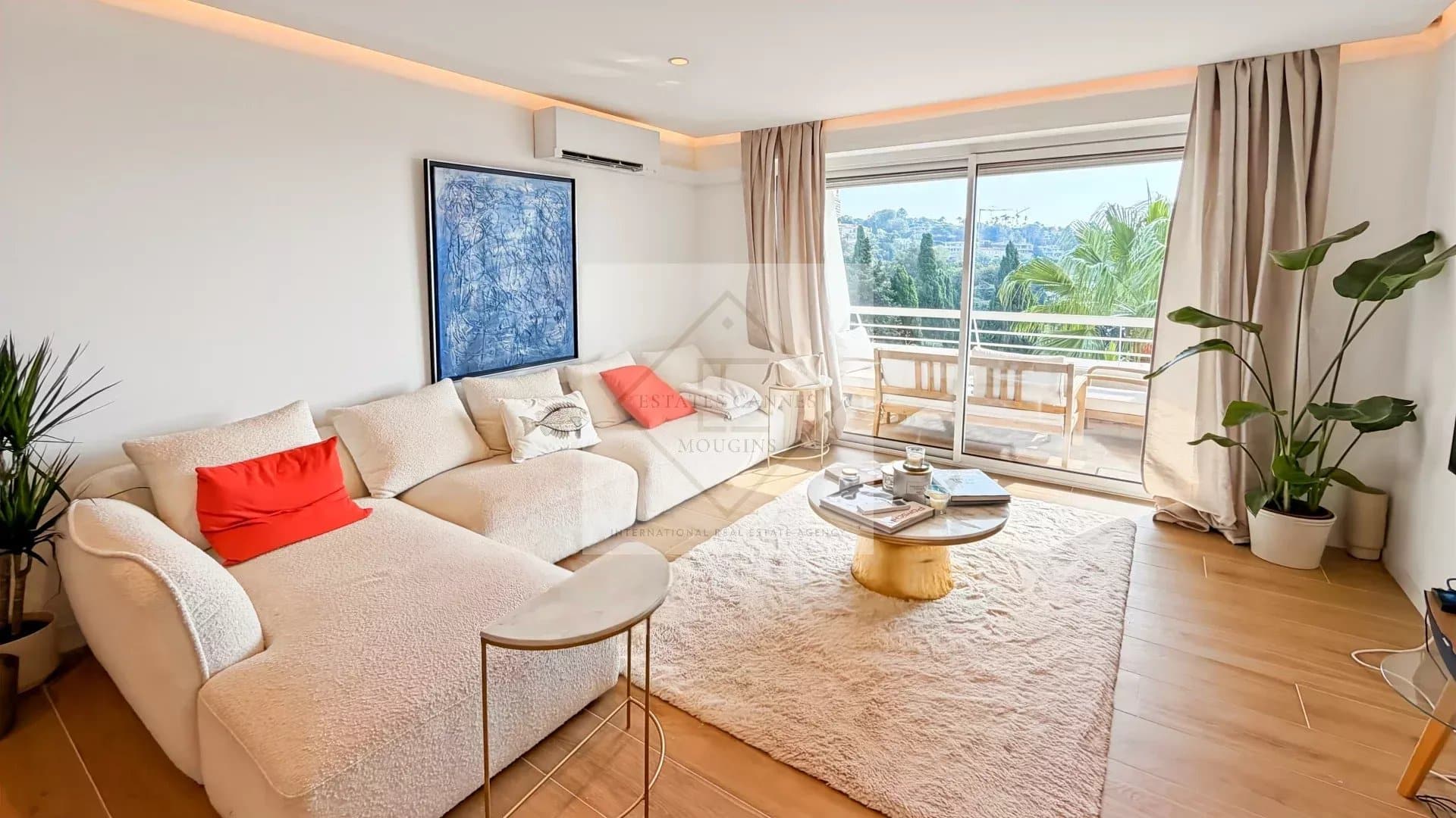 Salon lumineux d'un appartement rénové avec vue sur la mer, canapé et table basse.