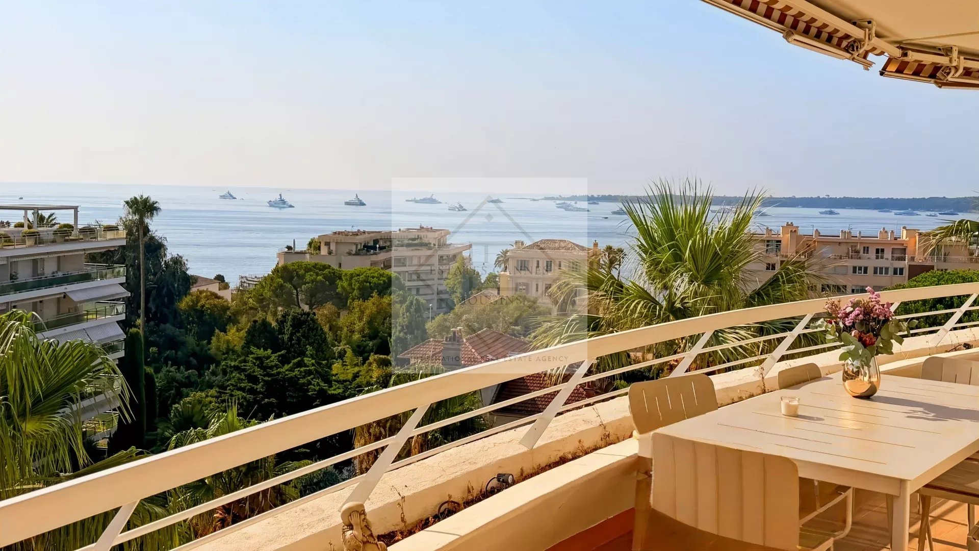 Vue panoramique sur la mer depuis une terrasse d'appartement à Cannes, avec des yachts au loin.