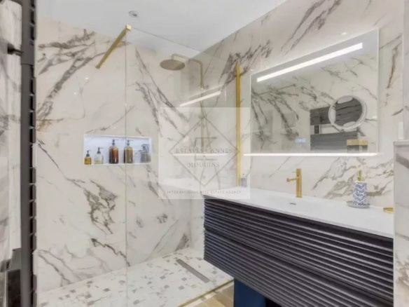 Salle de bain moderne avec douche à l'italienne et lavabo dans un appartement rénové.