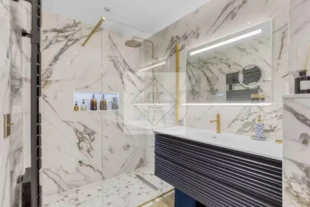 Salle de bain moderne avec douche à l'italienne et lavabo dans un appartement rénové.