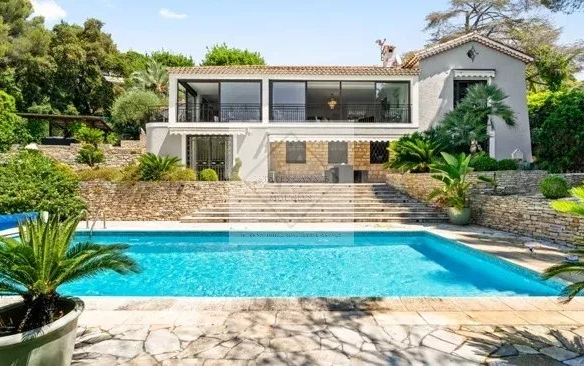Villa moderne avec piscine à Cannes, entourée de verdure et de palmiers.
