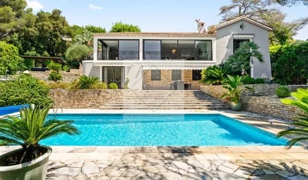 Villa d’exception à Cannes Villa moderne avec piscine à Cannes, entourée de verdure et de palmiers.