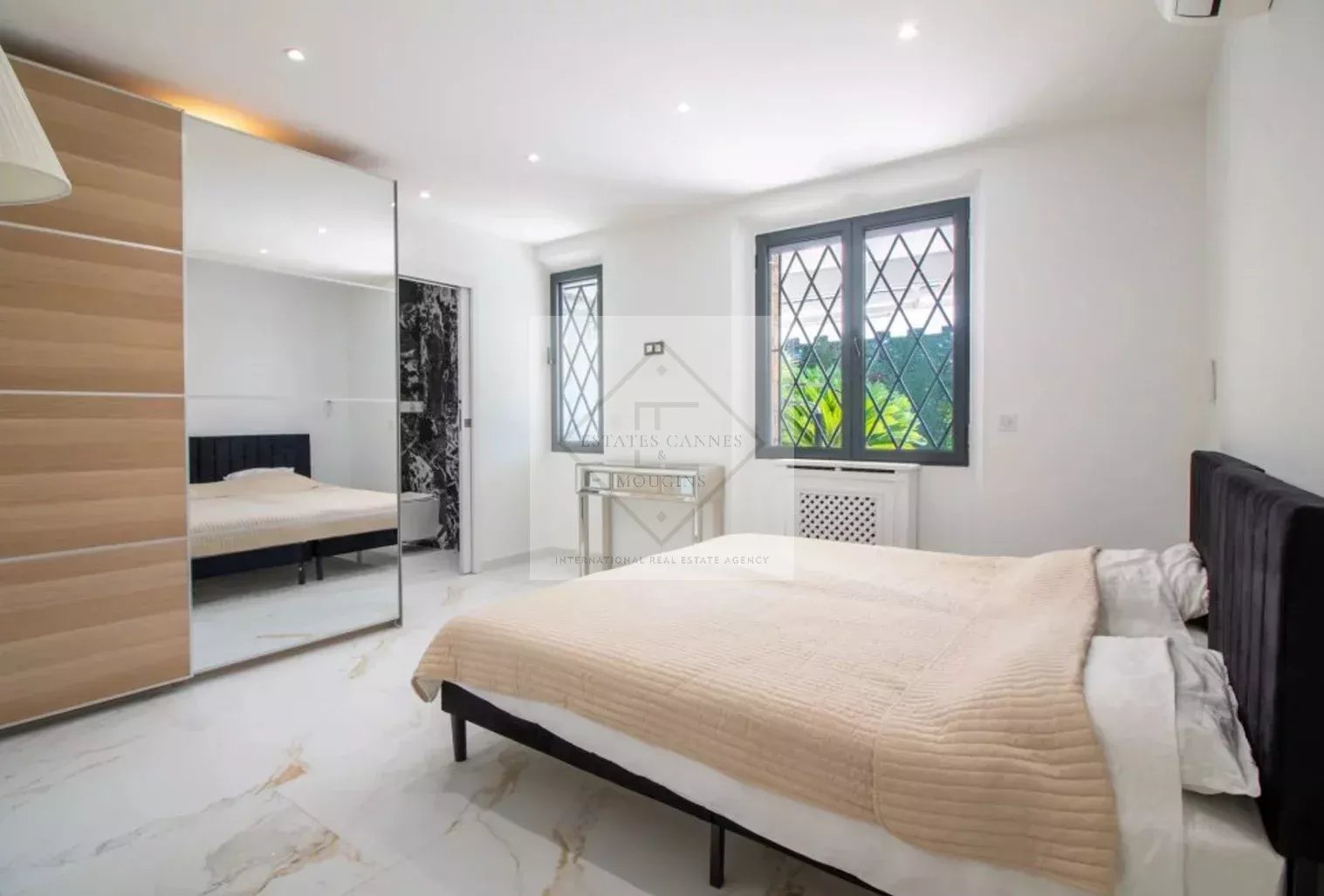 Chambre d’une villa à Cannes Chambre moderne et lumineuse d'une villa à vendre à Cannes, avec un lit et un grand miroir.