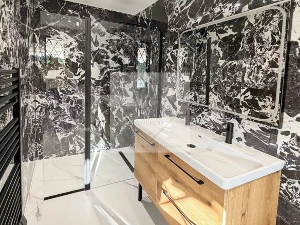 Salle de bain moderne avec murs en marbre noir et meuble en bois.