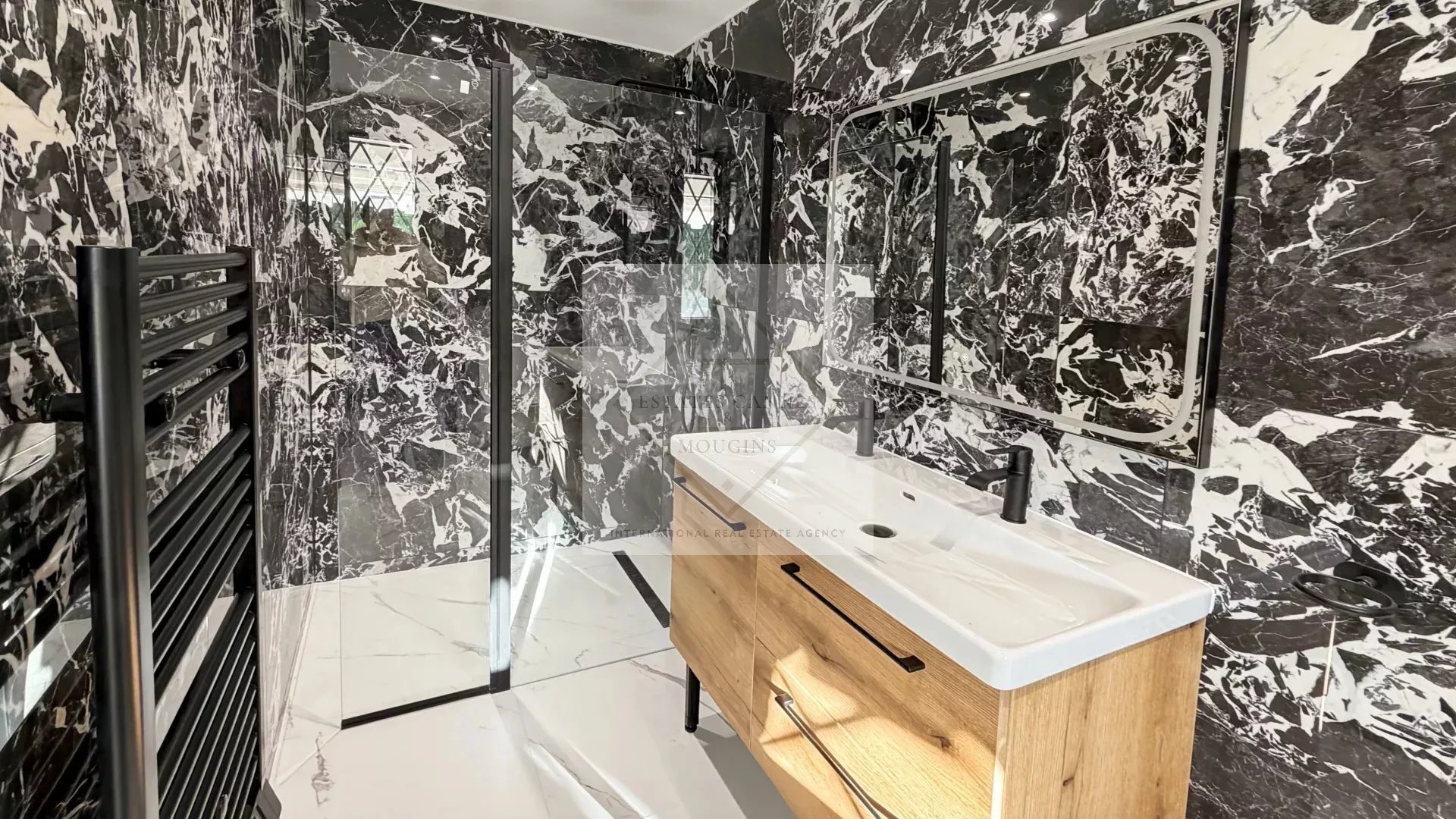 Salle de bain de villa à Cannes Salle de bain moderne avec murs en marbre noir et meuble en bois.