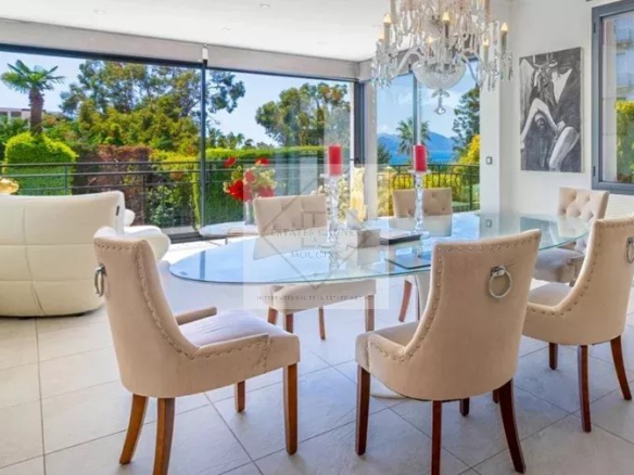 Intérieur d'une villa moderne à Cannes avec salle à manger élégante et vue sur la nature.