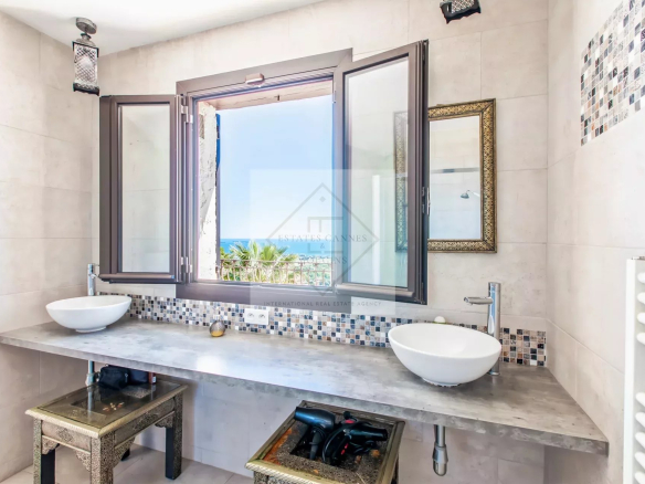 Salle de bain avec vue sur la mer et fenêtres ouvertes à Mandelieu-la-Napoule.
