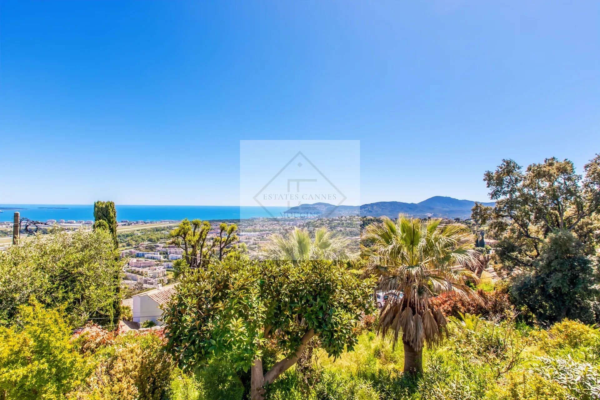 Villa d’exception avec vue mer à Cannes Vue panoramique sur la mer depuis une villa à Cannes, entourée de verdure.