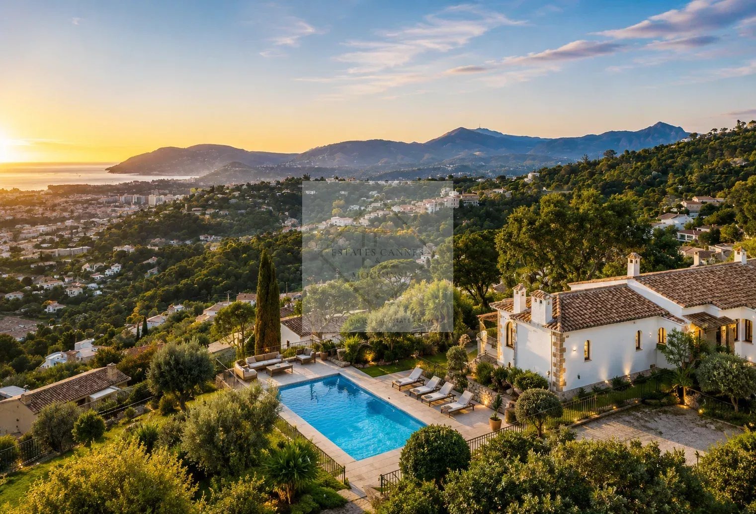 Villa d’exception à Cannes Vue panoramique d'une villa avec piscine à Cannes, entourée de verdure et de montagnes au coucher du soleil.