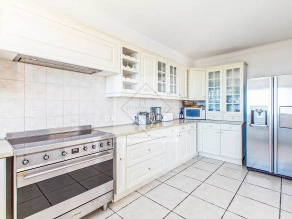 Cuisine moderne et lumineuse d'une villa avec des meubles blancs et des appareils électroménagers en acier inoxydable.