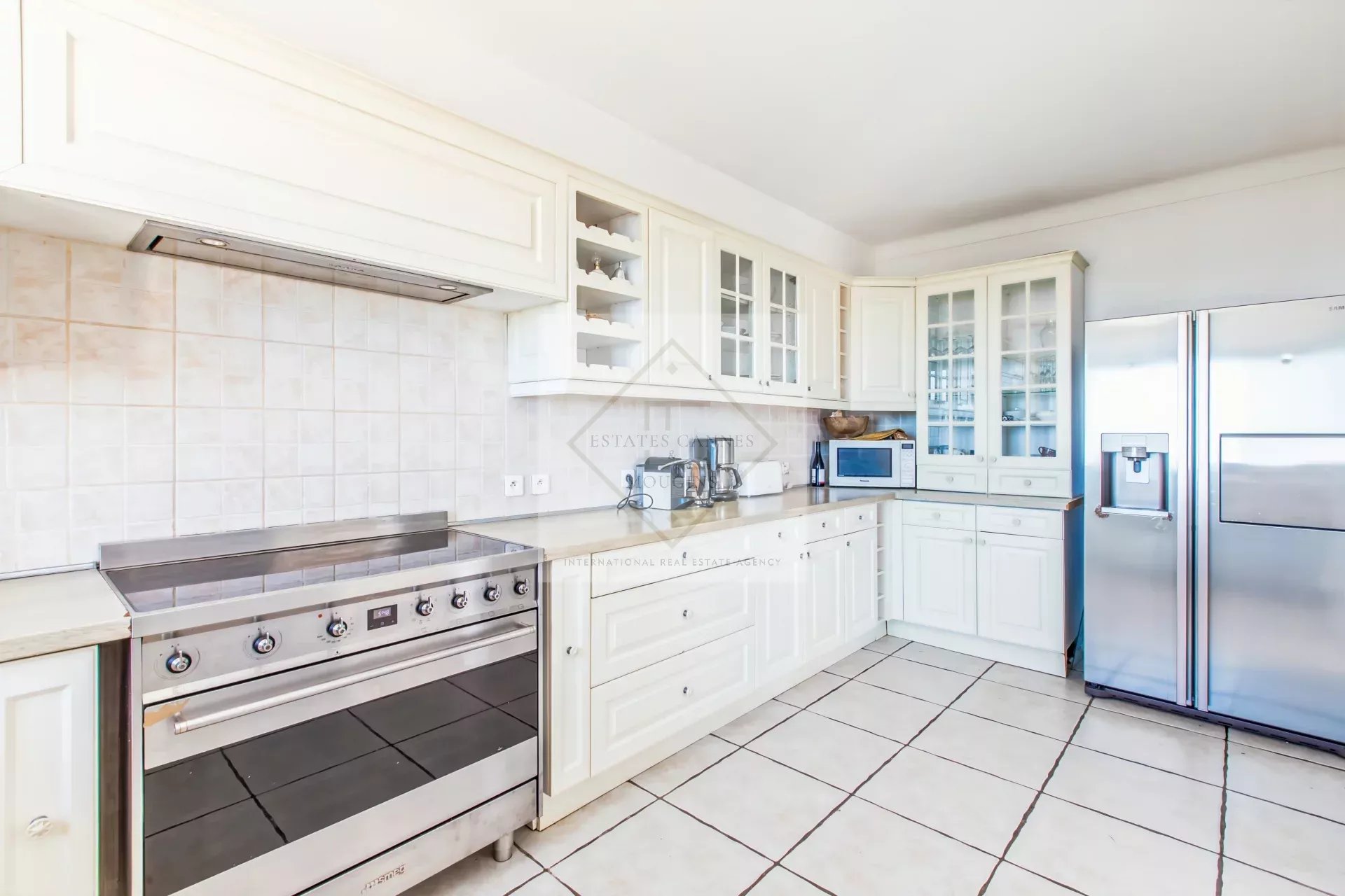 Cuisine d’une villa d’exception à Cannes Cuisine moderne et lumineuse d'une villa avec des meubles blancs et des appareils électroménagers en acier inoxydable.