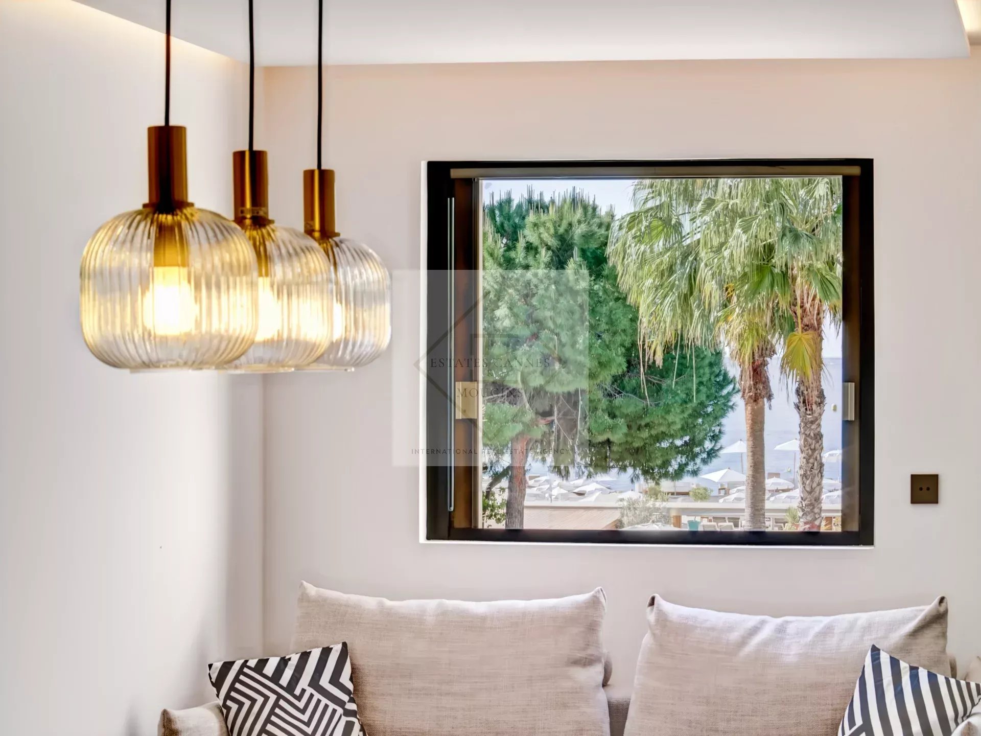 Interior of an apartment with hanging lamps and a view of palm trees in Cannes.